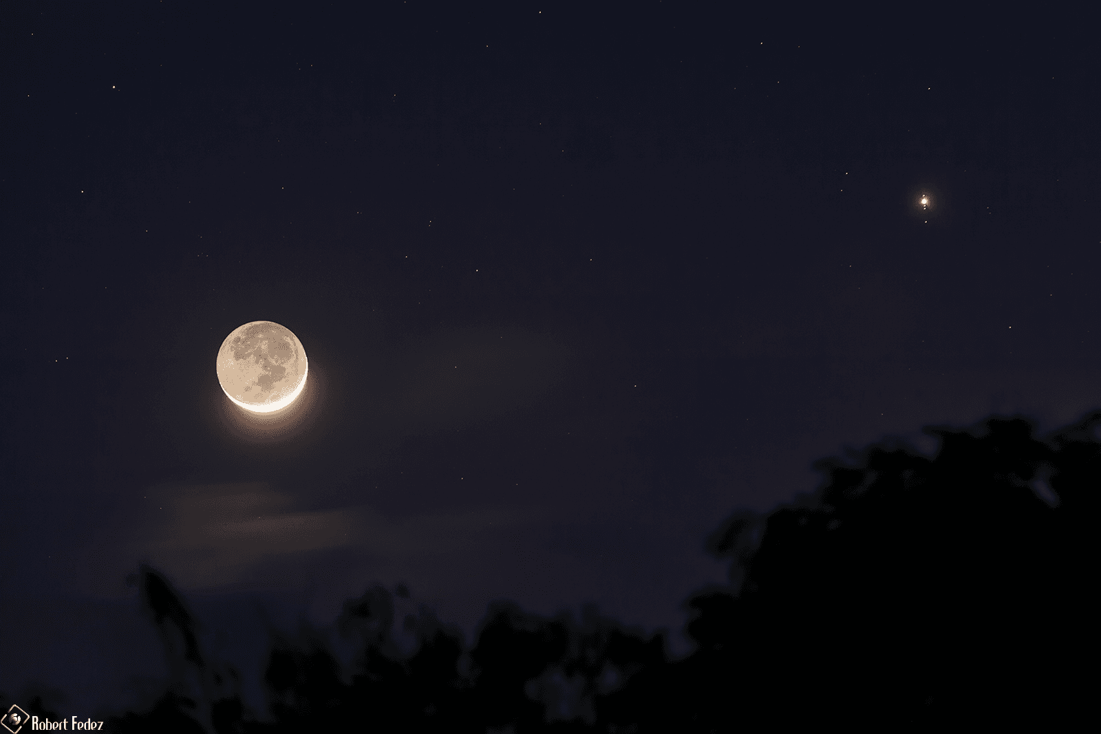قمرٌ بطور الهلال حيث يظهر أسفلهُ مناراً بضوء الشمس والباقي بألق الأرض، بينما يظهر المشتري على اليمين صغيراً ساطعاً وتطصفّ معه أقماره الگاليليّة واحدٌ فوقه والثلاثة الباقية تحته