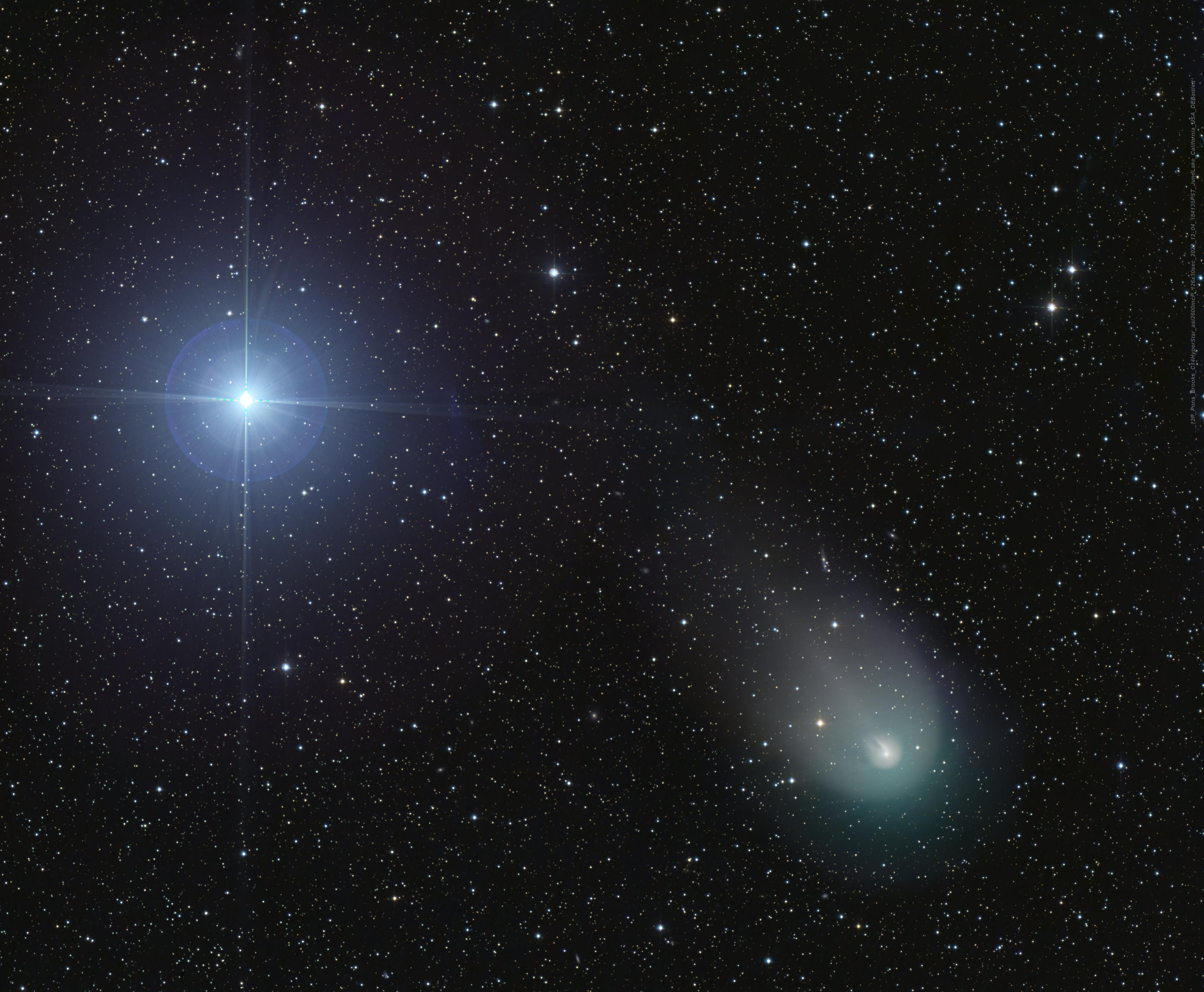 نجمُ ساطع يظهر بدوائر ضوء وشوكات حيود، وبجانبه مذنّب بذؤابة مخضرّة على خلفيّة من النجوم التي تظهر أخفت وأصغر