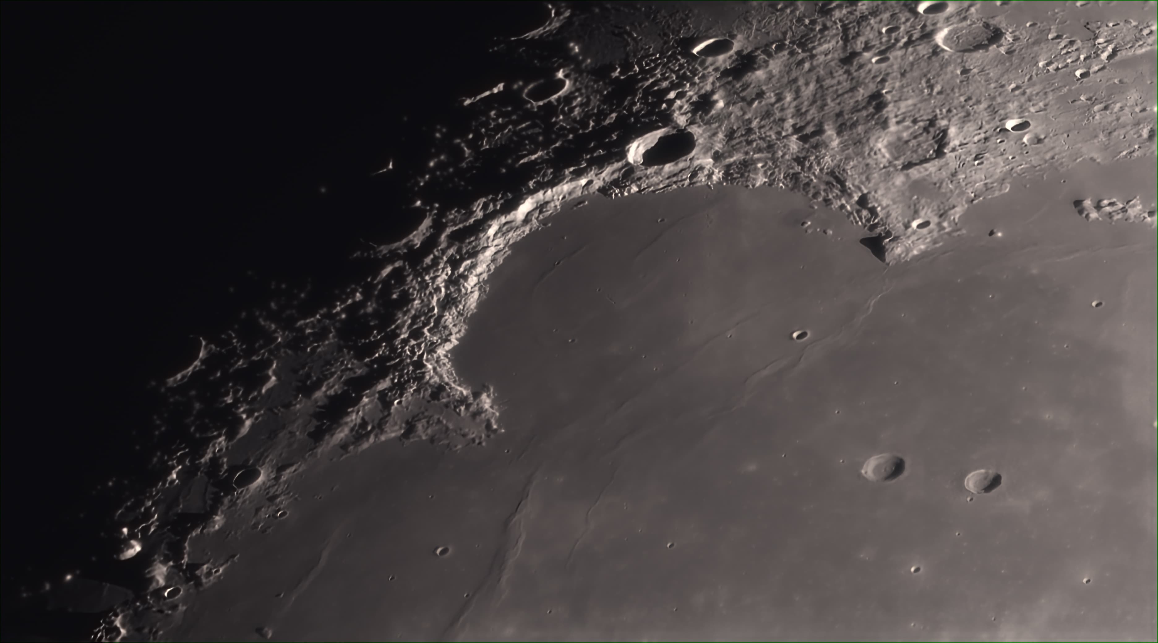 جزء من سطح القمر مُنار من الجانب تظهر فيه مساحة كبيرة ملساء تحدّها تضاريس ذات فوّهات