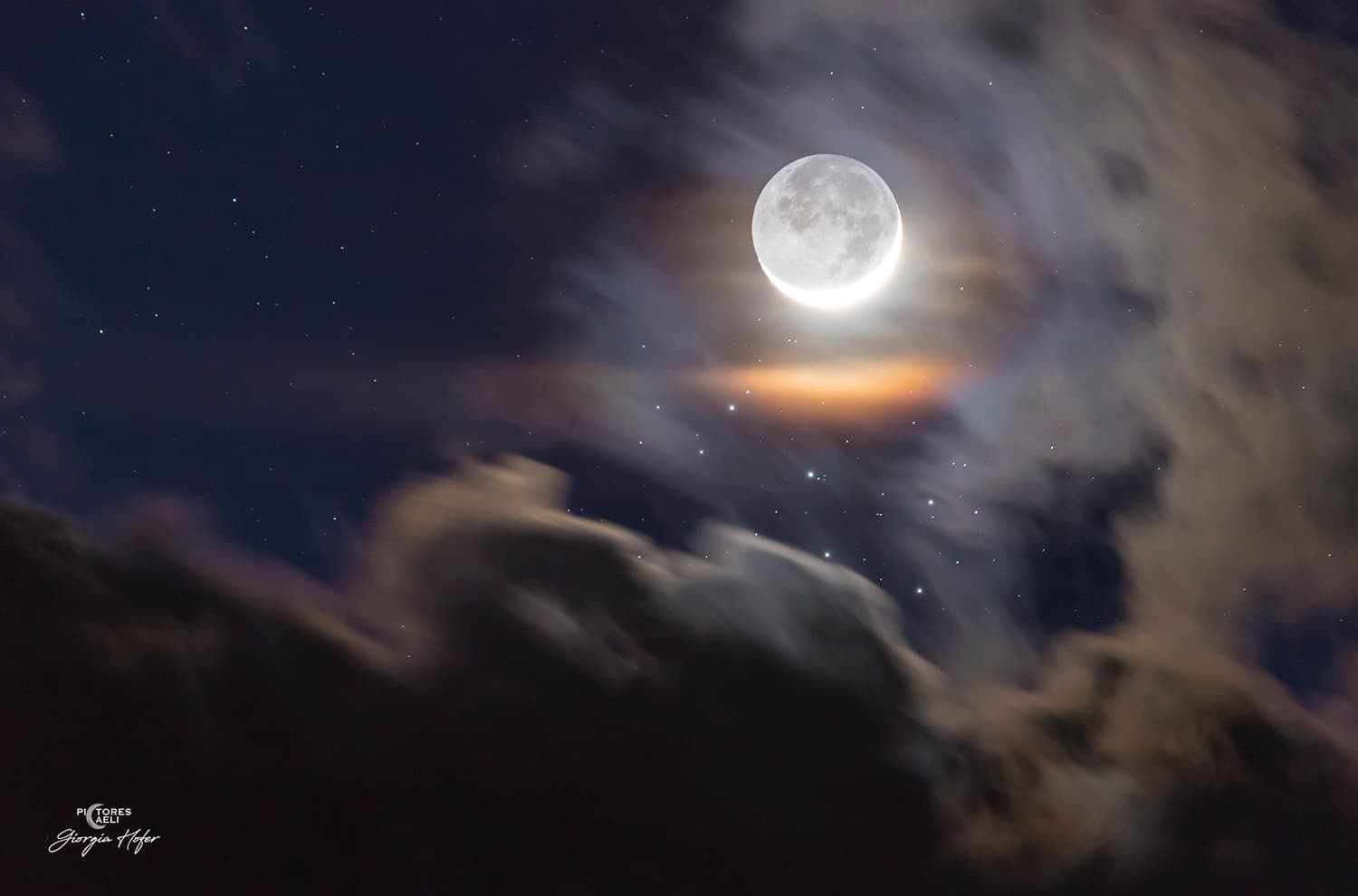 قرص القمر خافتٌ بالمعظم وعلى جانبه هلال يحيط به إكليل قمري ملوّن تتخلّله نجوم منها عنقود الثٌُّريّا مع امتداد غيوم على جانبَين من الإطار