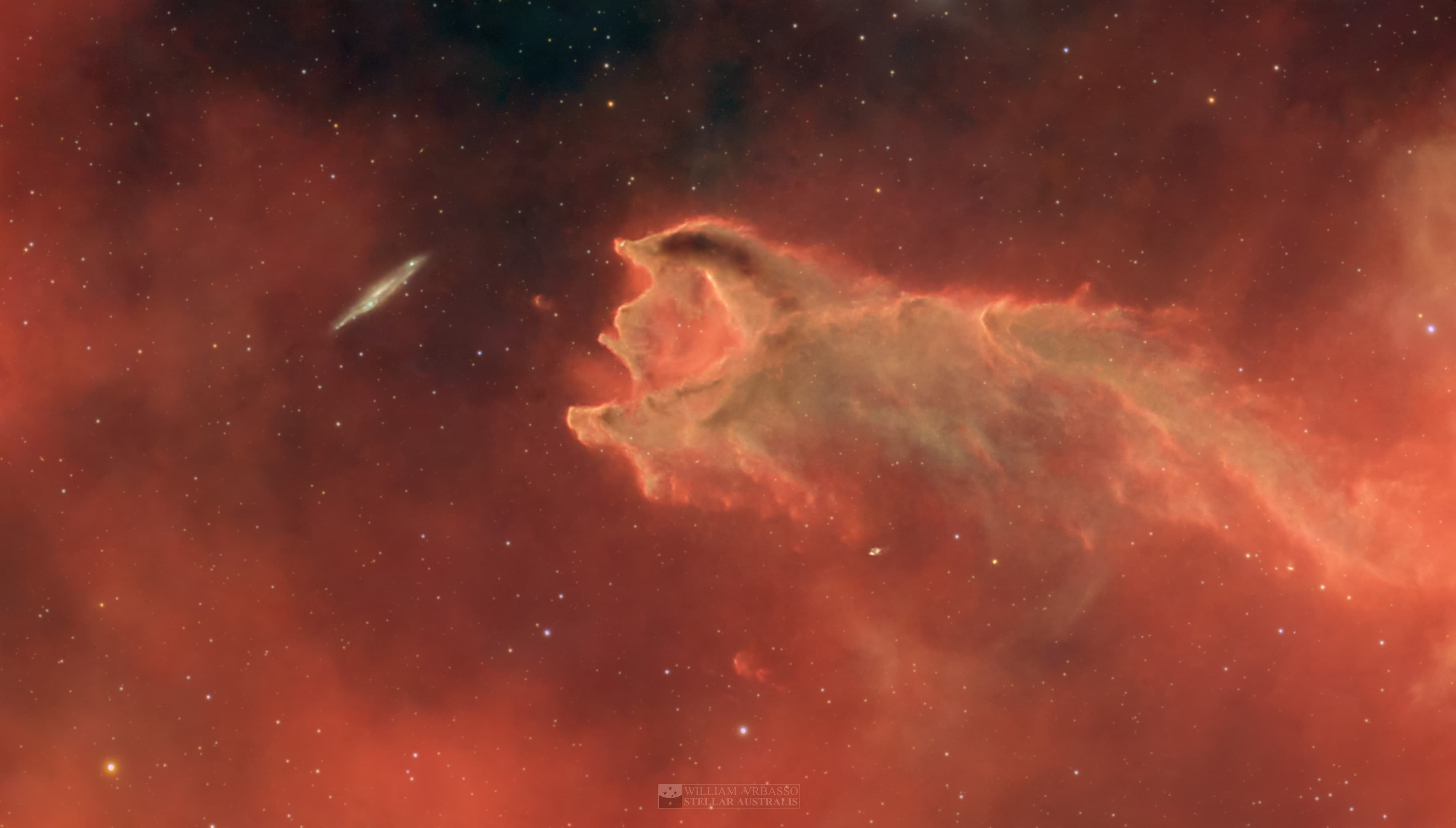 تمتدّ كُريّة مذنّبيّة أمام حقل من النجوم، مُظهِرةً ما يبدو كفمٍ مفتوح باتِّجاه مجرَّةٍ بعيدةٍ في الخلفيّة.